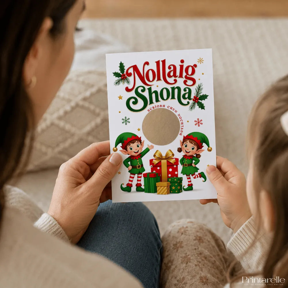 A festive white nollaig shona scratch reveal card with two cartoon irish language elves in green and red outfits