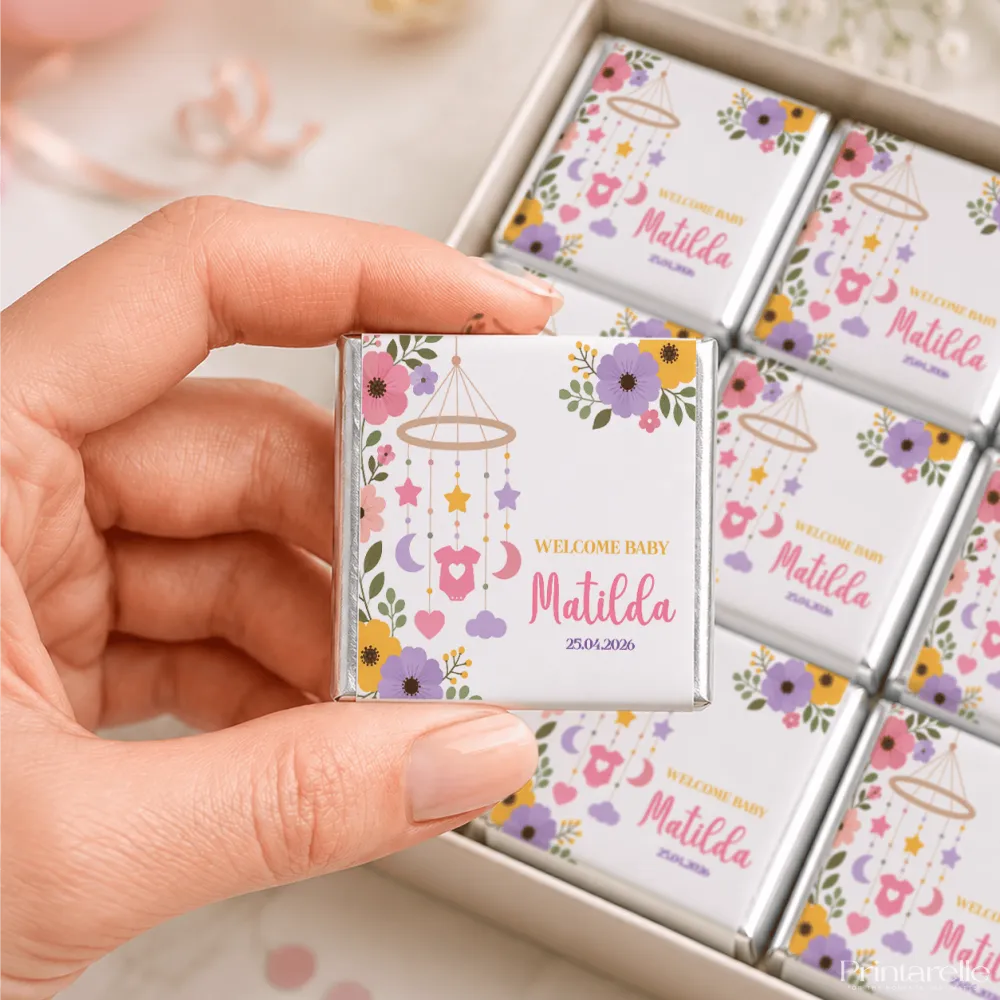 A white chocolate square with a nursery mobile design featuring pink purple yellow flowers and stars mini neapolitan chocolates