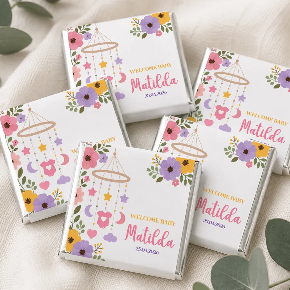 White chocolate-wrapped mini neapolitan chocolates with colorful nursery mobile designs for welcome baby events