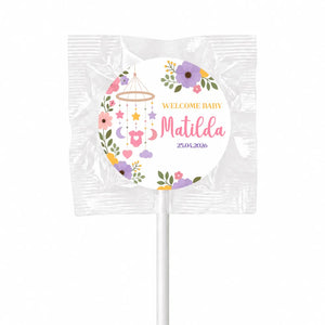A sweet round swirl lollipop favour wrapped in clear plastic with colorful welcome baby matilda nursery mobile design