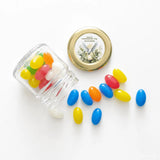 Clear glass mini jar with pale gold twist lid spilling colorful jelly beans from peaceful dove confirmation set