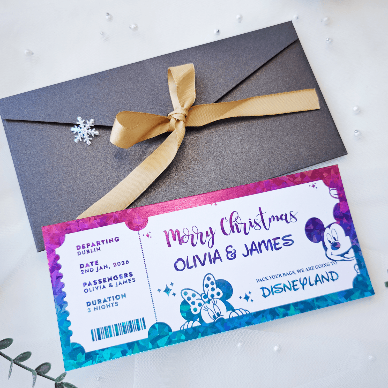 Christmas-themed Disneyland ticket with a gray envelope and gold ribbon on a white background