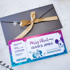 Christmas-themed Disneyland ticket with a gray envelope and gold ribbon on a white background