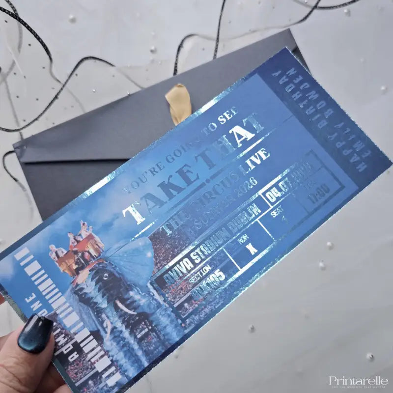 Blue concert ticket with 'Take That' on a gray surface