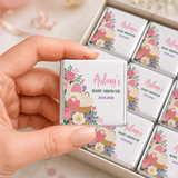 A silver wrapped mini neapolitan chocolates bar with pink and purple floral design for pink bassinet baby shower