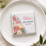 A personalized white chocolate bar with floral and baby basket design wrapped in silver foil for aisling baby shower featuring mini neapolitan chocolates