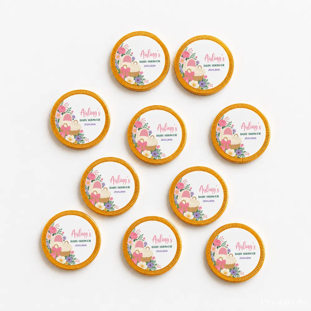 Round gold-rimmed chocolate coins with pink bassinet floral design for baby shower favors