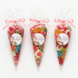 Three clear plastic sweet cones tied with pink ribbons filled with gummy candies perfect for pink bassinet baby shower