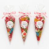 Three clear plastic sweet cones tied with pink ribbons labeled olivias first holy communion filled with colorful gummies pink church communion