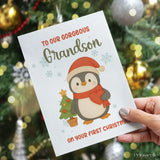 Christmas card with a penguin illustration and text held in front of a decorated Christmas tree.