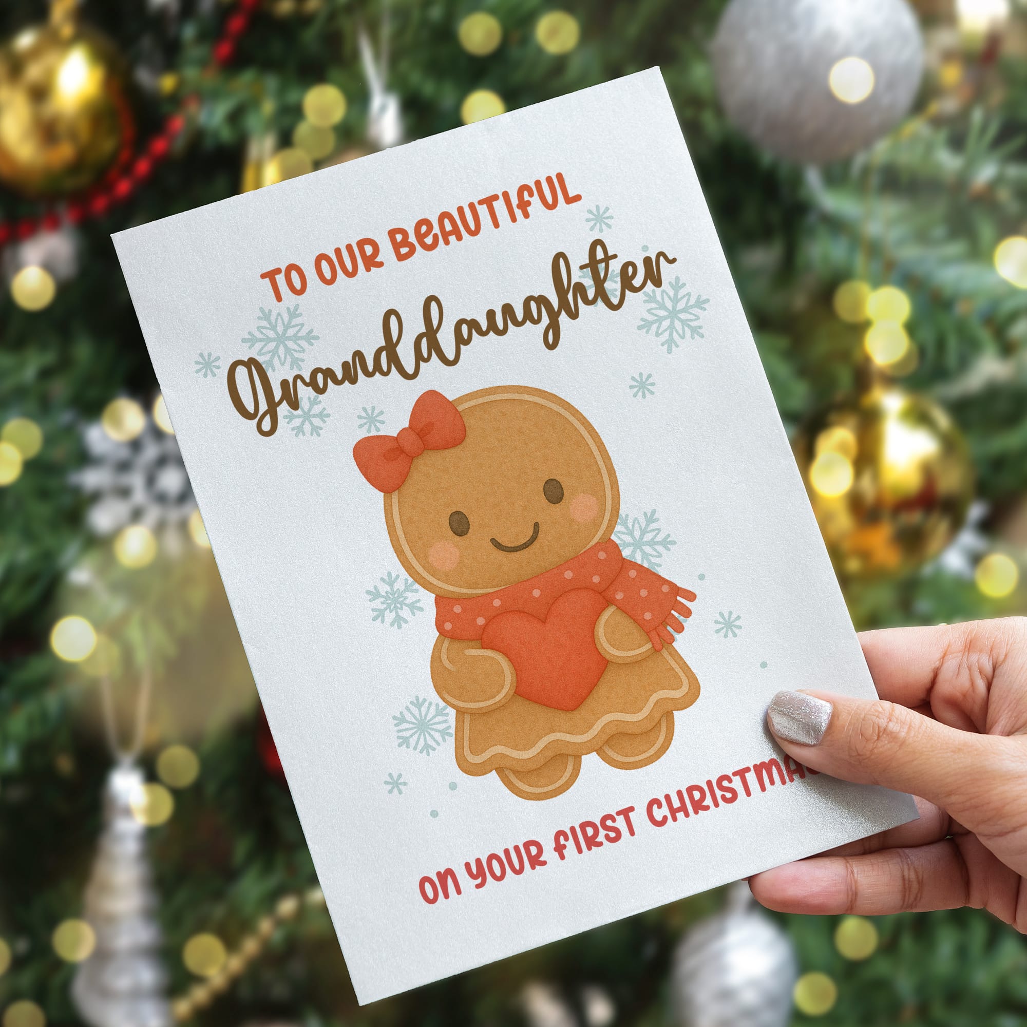 Greeting card for a granddaughter's first Christmas held in front of a decorated Christmas tree.