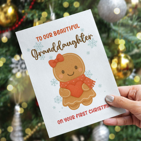 Greeting card for a granddaughter's first Christmas held in front of a decorated Christmas tree.