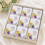White chocolate mini neapolitan chocolates with gold foil and decorative paper featuring a golden chalice and grapes