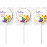 Three wrapped fruit lollipops with colorful foil featuring a gold chalice purple grapes and personalised first holy communion text