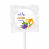 A white wrapped fruit lollipop favour with purple and gold text and a golden chalice for first holy communion