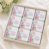 Nine mini neapolitan chocolates individually wrapped in white paper with rainbow and floral designs for baby showers