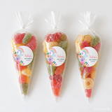 Three clear plastic sweet cones filled with colorful gummy candies perfect for rainbow blooms baby shower treats