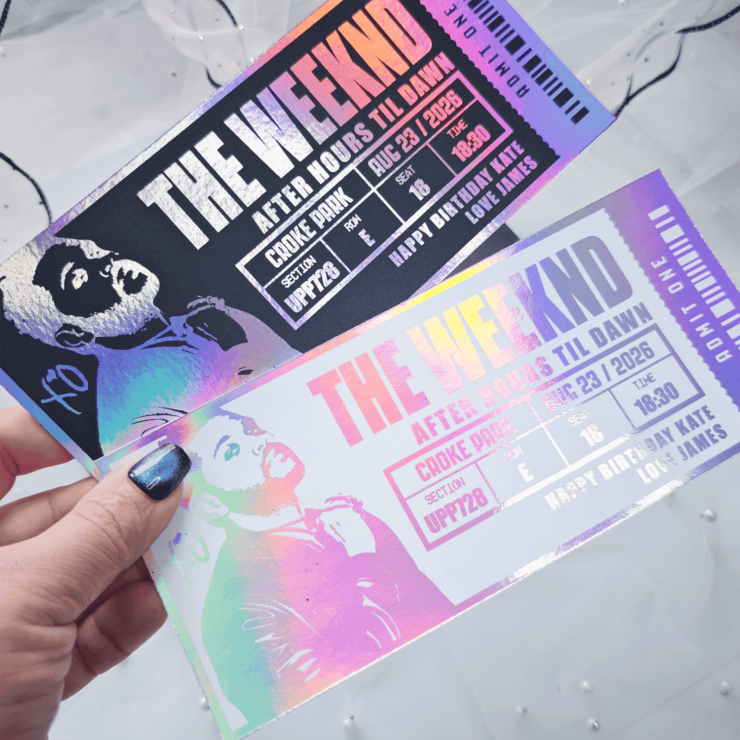Two concert tickets for 'The Weeknd' held by a hand on a light gray background