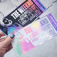 Two concert tickets for 'The Weeknd' held by a hand on a light gray background
