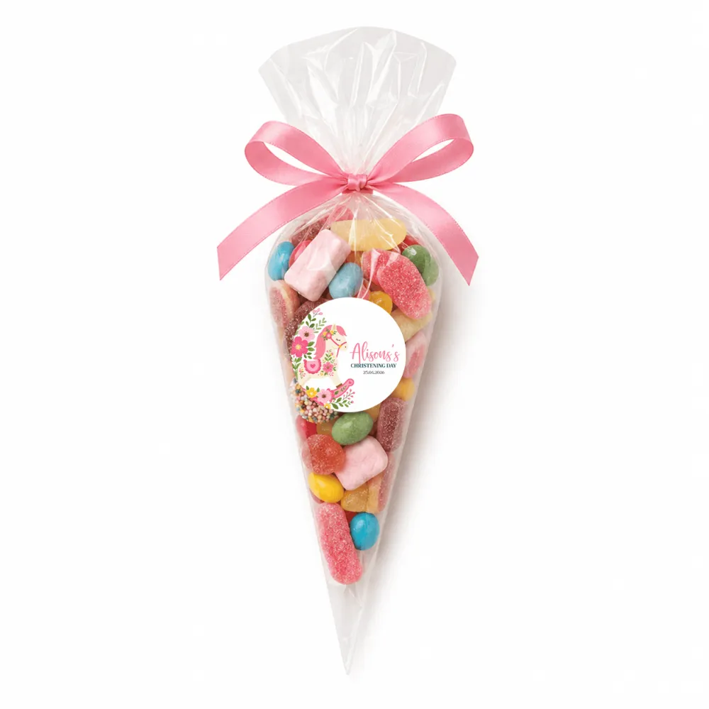 A clear plastic sweet cone filled with colorful gummies tied with a pink ribbon for rocking horse christening gifts