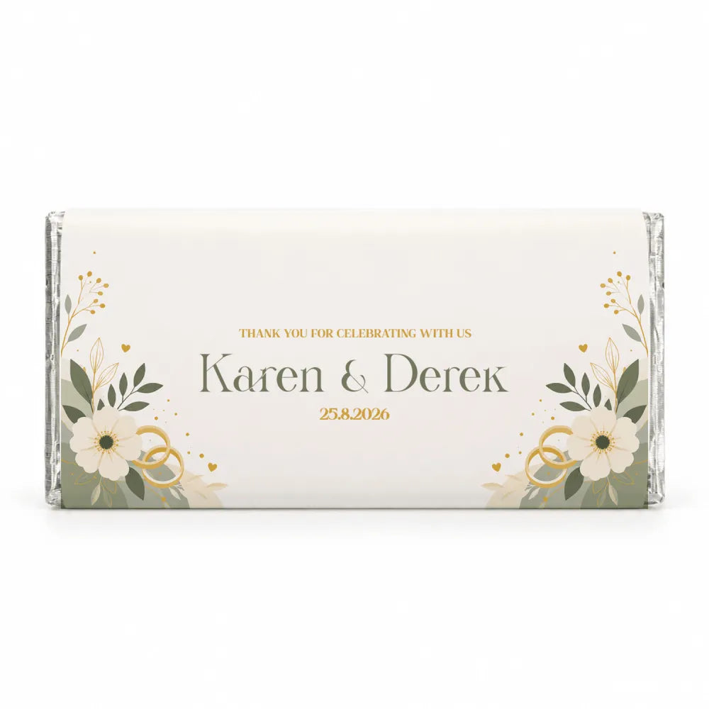 A personalised 40g chocolate bar wrapped in elegant foil with cream flowers green leaves and gold accents for weddings