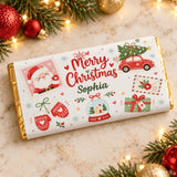 A personalized white chocolate bar wrapper with festive red green and gold christmas illustrations and a waving santa stamp