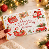 A personalized white chocolate bar wrapped in festive red and gold foil with santa sleigh, retro typewriter, and mailbox design