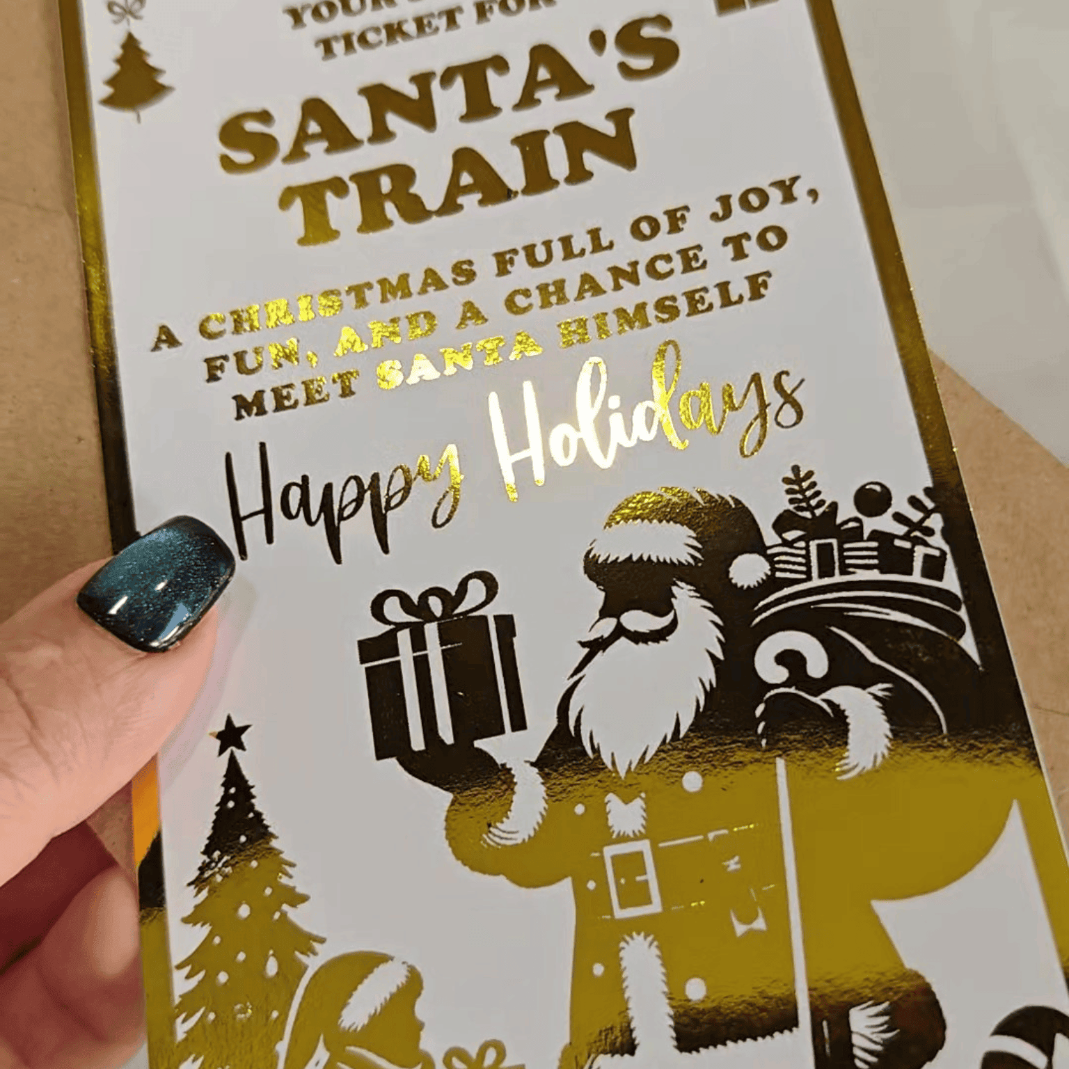 Card with Santa Claus illustration and Christmas-themed text, held by a hand.