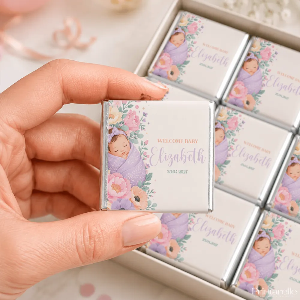 A delicate square-shaped mini neapolitan chocolate bar wrapped in silver foil with lavender and pink floral design featuring a sleeping baby illustration