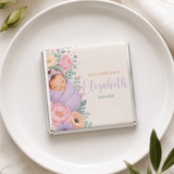 A personalized mini neapolitan chocolate bar wrapped in silver foil with a sleeping baby and floral design
