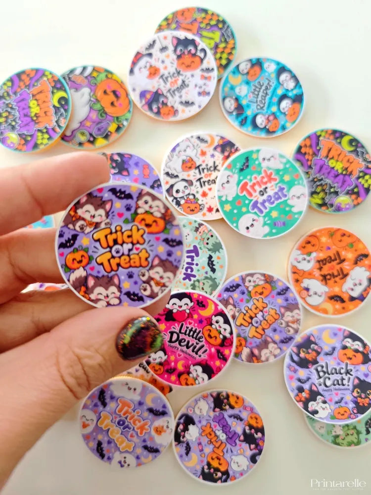 A hand holds a spooky cute circular 40mm milk chocolate coin sticker with halloween cats pumpkins and bats design