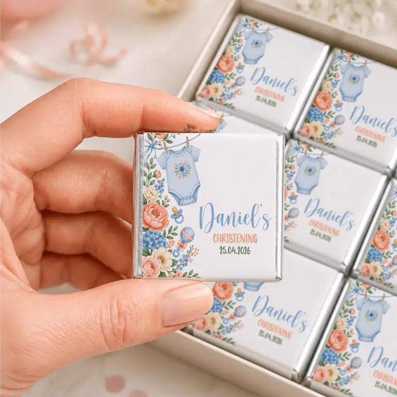 A delicate square silver foil wrapped mini neapolitan chocolate with blue onesie and floral design for christening