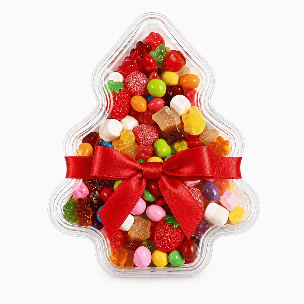 A clear tree shaped christmas tree container filled with colorful gummies and tied with a red satin bow perfect for personalised stickers