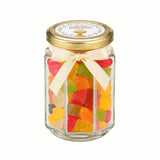 A clear 106ml glass jar with a gold lid and cream ribbon bow filled with colorful gummy bears for party favours with a 48mm pale gold personalised sticker