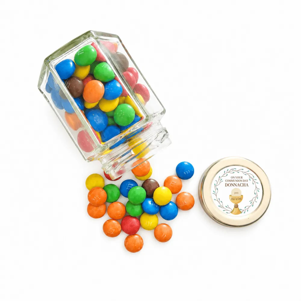 Clear glass hex jar filled with colorful m&m’s candies, gold-rimmed lid, personalised 48mm pale gold sticker, party favours