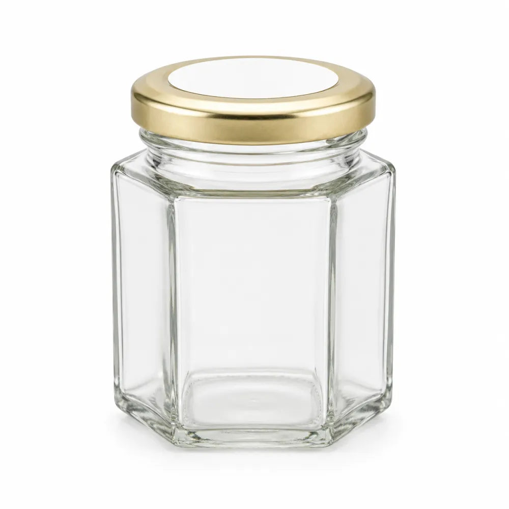 Clear hexagonal glass jar with pale gold twist lid and 48mm pale gold personalised sticker for sweets party favors