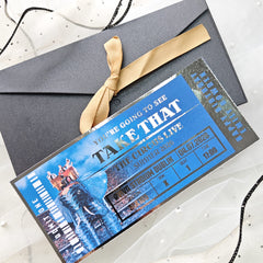 Promotional ticket for 'Take That' circus live event with a gold ribbon on a white background