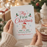 A tiny hands big magic christmas card with a white base, beige teddy in red santa hat, holly, and my first christmas text