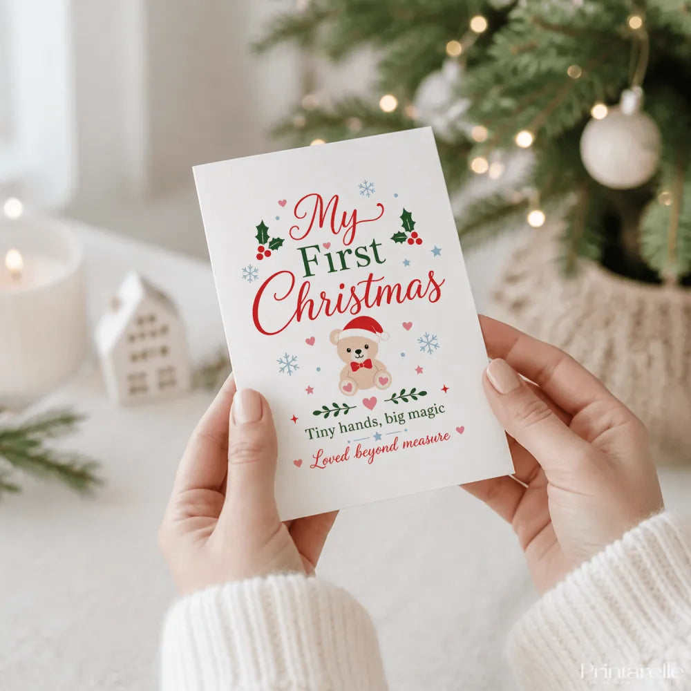 A white tiny hands big magic christmas card with festive holly hearts and teddy first christmas text in red and green