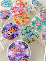 Colorful assorted fruit lollipops with halloween cartoon characters black cat and trick or treat text on glossy surfaces