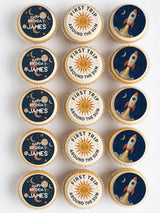 Vintage space first birthday cupcake toppers with rockets suns and planets on dark blue icing sheet for birthday cupcakes