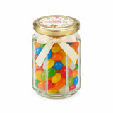 A clear glass hex jar favour filled with colorful jelly beans and a 48mm pale gold twist lid with cream ribbon bow