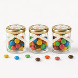 Three clear glass jars with 43mm pale gold lids and personalised sticker printed for wildflower blessing favours