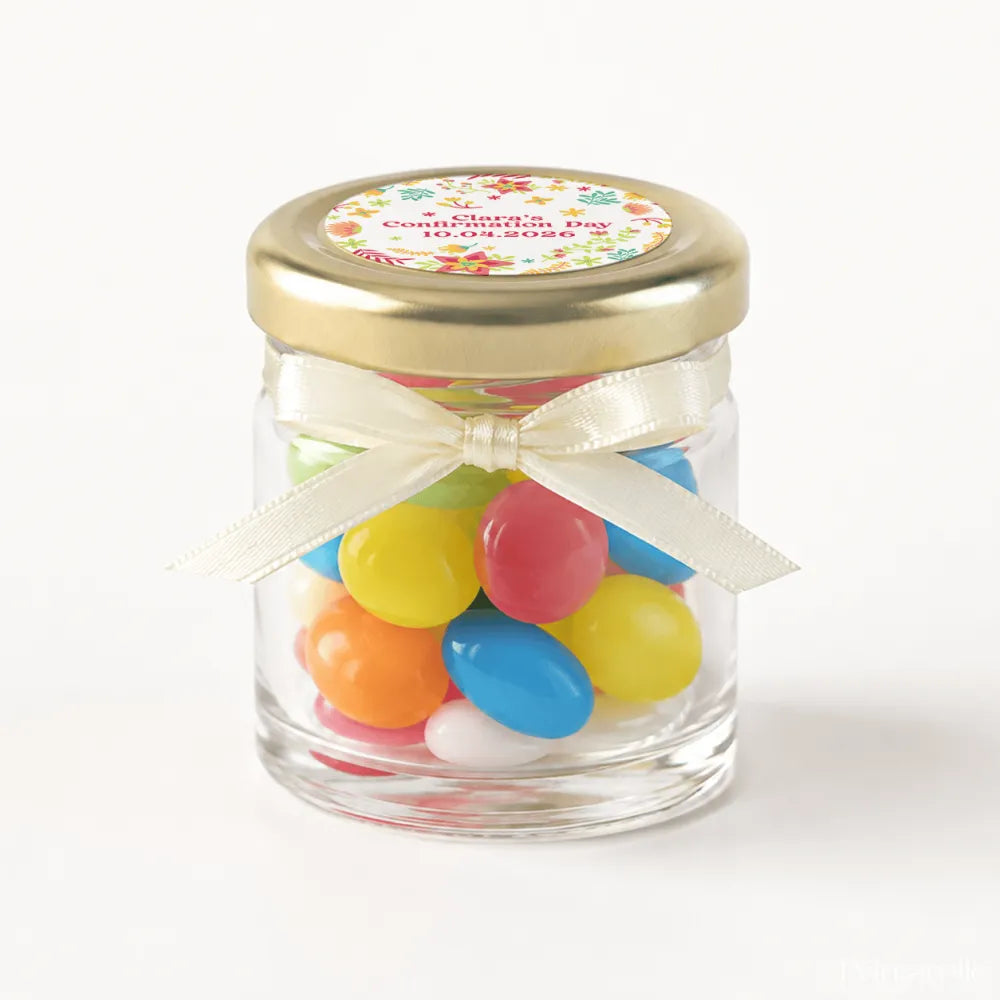 A personalised mini jar favour filled with colorful jelly beans in a clear glass jar with 43mm pale gold lid and cream bow