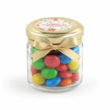 A clear glass jar favour filled with colorful m&m’s in a 43mm pale gold twist lid with a personalised sticker printed